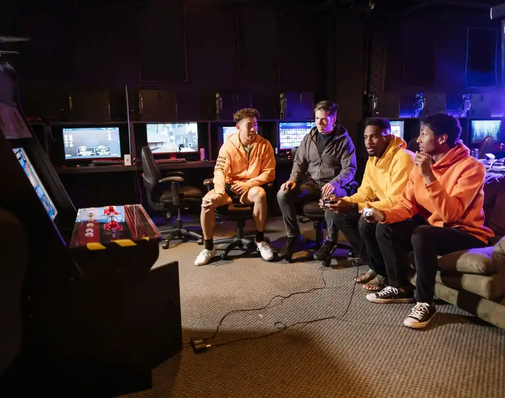 Four friends laughing together in a neon-lit games lounge